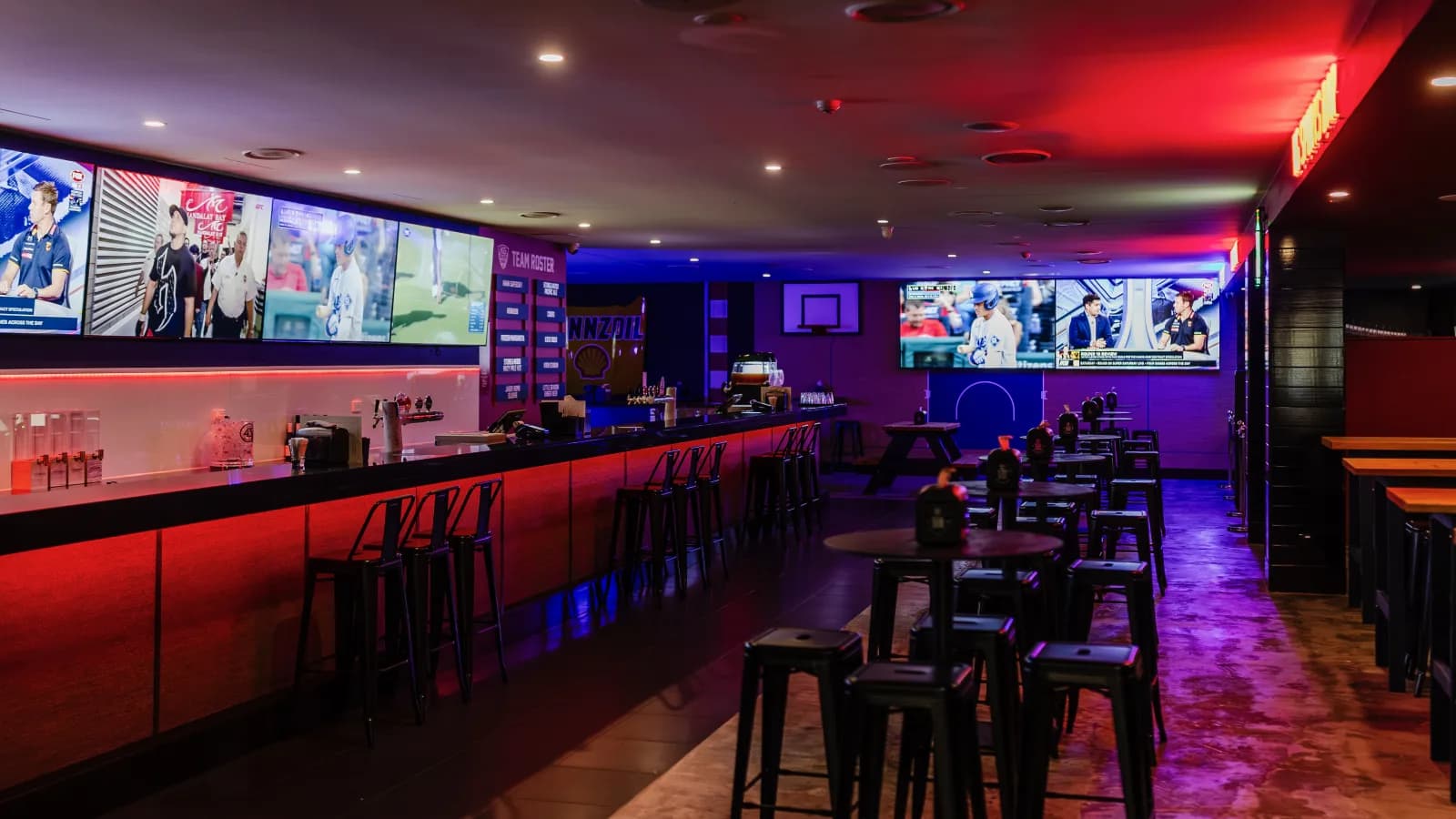 KG Sports Bar interior with a wall of live sports screens above the bar